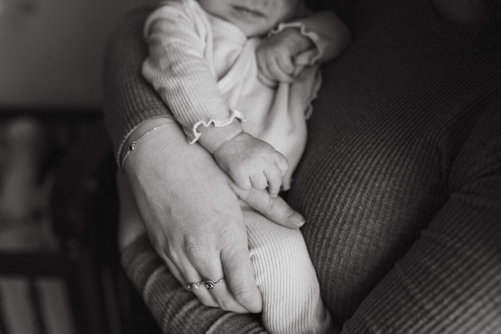 Newborn holding mom’s finger during an in-home session with a North Carolina family photographer