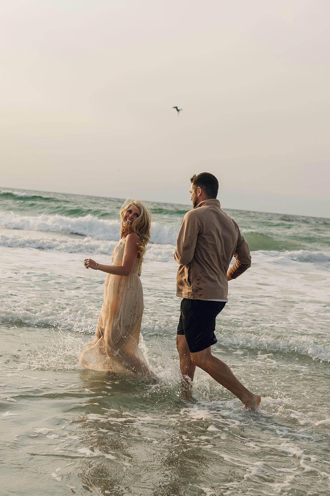 Couple barefoot in the waves during a Wrightsville Beach photo session