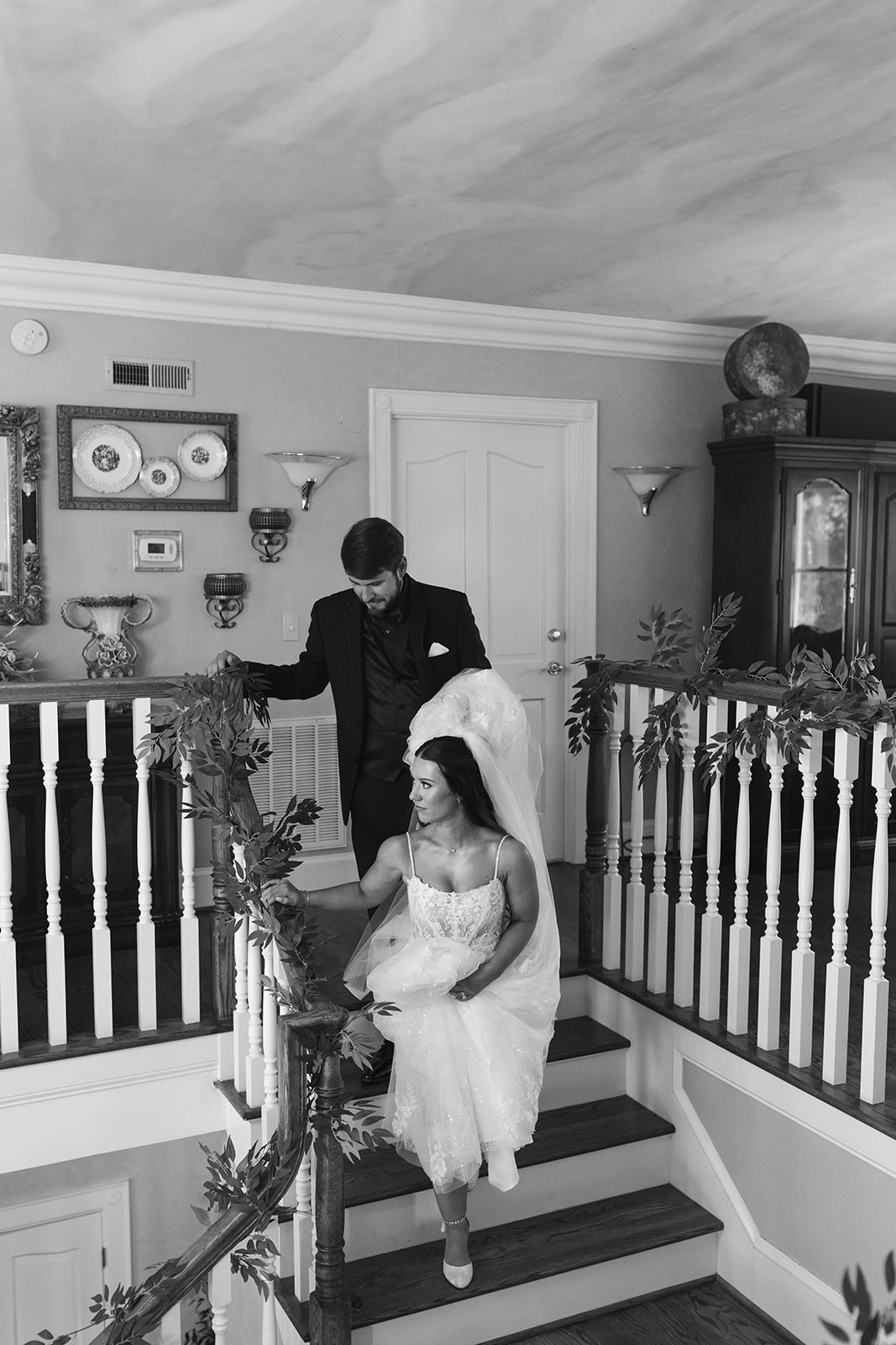 Groom carrying bride’s dress as they walk down stairs at a North Carolina wedding