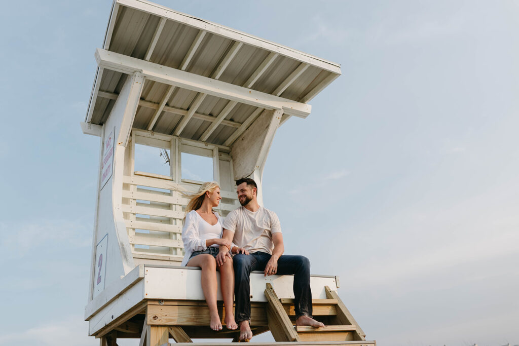 Couple sitting on Wrightsville Beach lifeguard tower during couples session